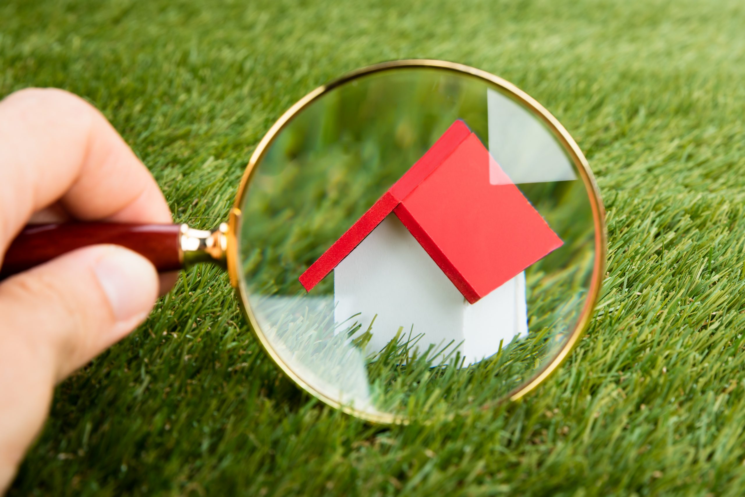 Magnifying Glass Inspecting A Model House